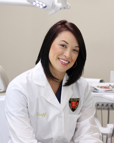 A woman in white lab coat sitting at desk.