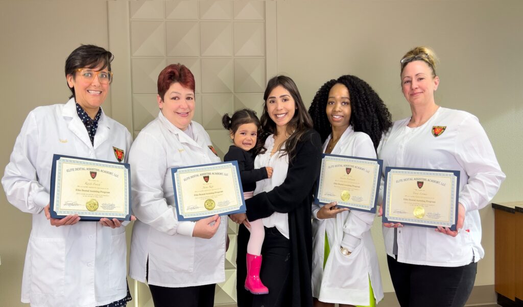 A group of doctors holding certificates and posing for the camera.
