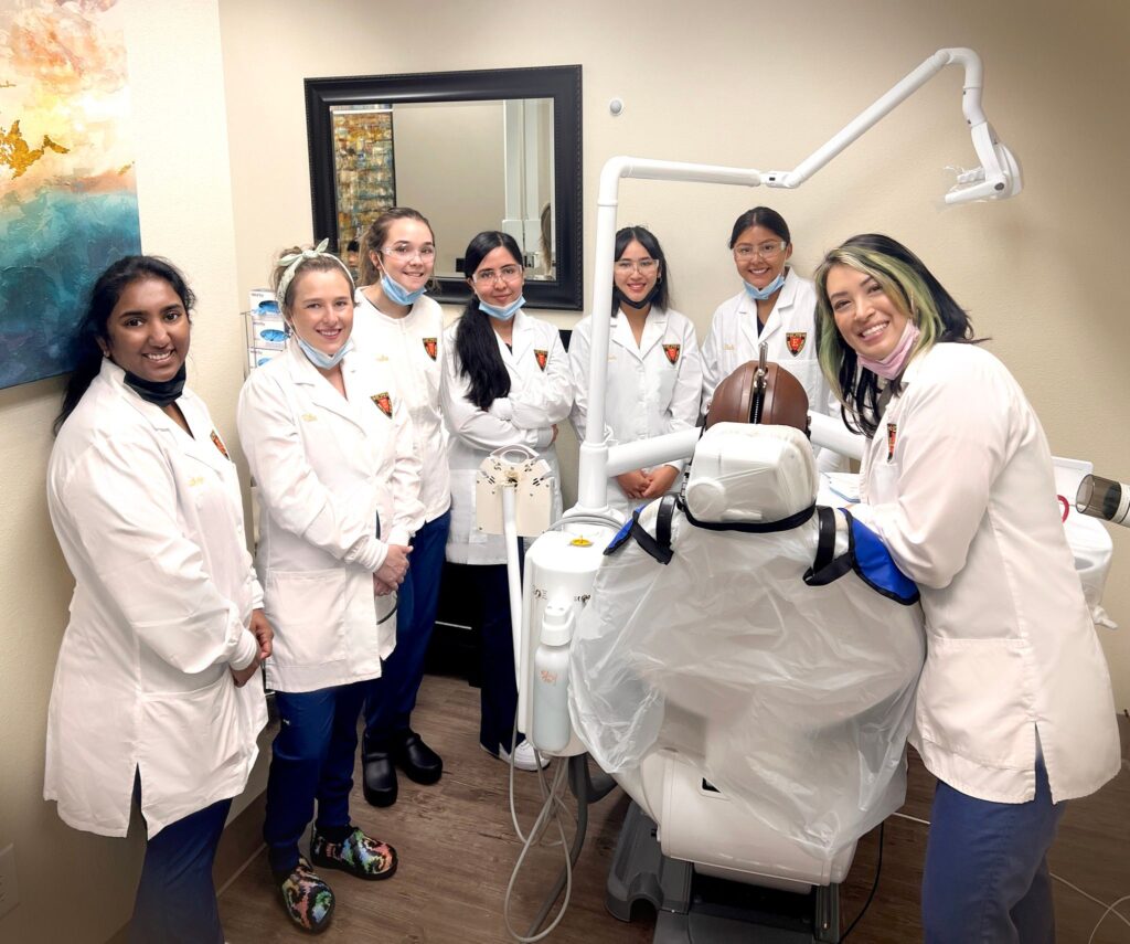 A group of doctors standing around a dentist 's chair.