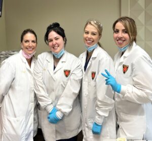 A group of women in lab coats and blue gloves.