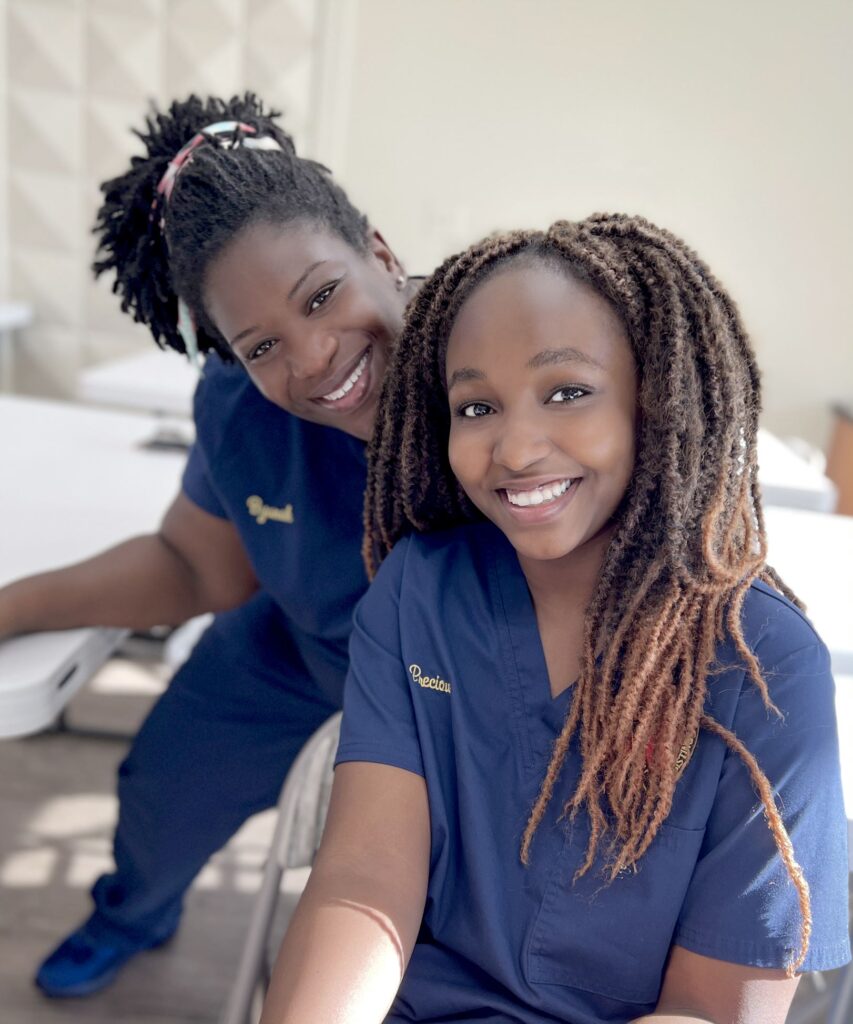 Two women in scrubs smiling for the camera.