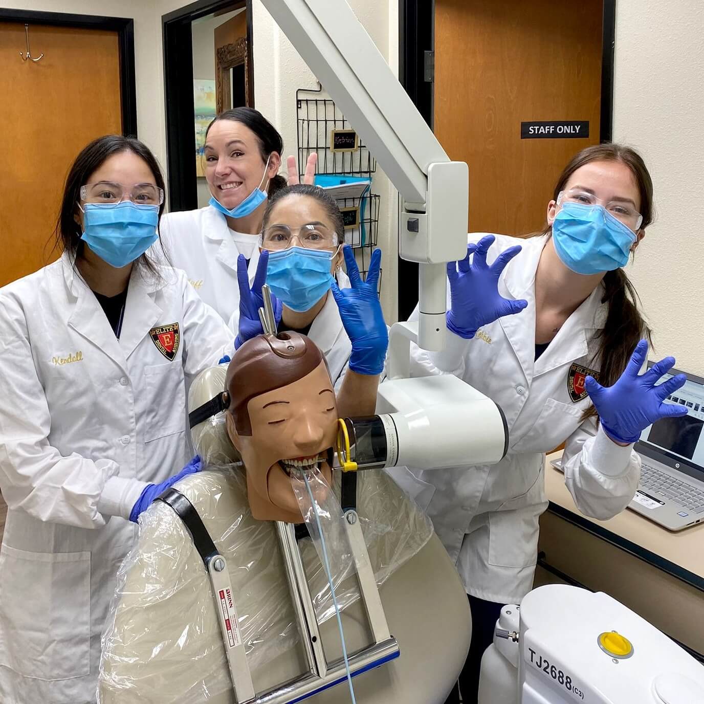 Four dental students smiling in a classroom.